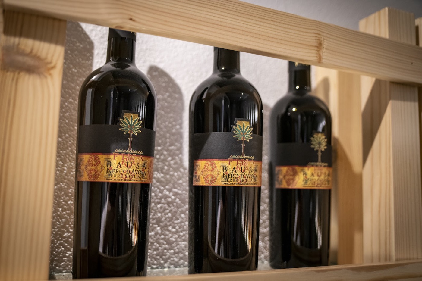 Bottiglie di Nero d'Avola siciliano sulla scaffalatura in legno